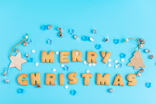 Cookies lettres joyeux Noël sur la surface bleue.