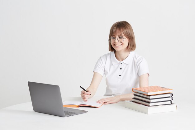 Cool femme heureuse passe par la formation en ligne assis à la maison. Enseignement scolaire à distance sur un ordinateur portable. Cours à domicile.