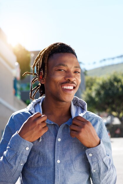 Cool gars africain avec des dreadlocks souriant à l&#39;extérieur