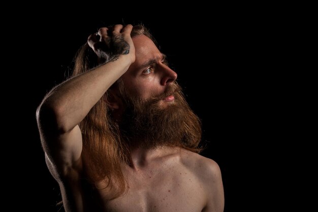 Cool hipster barbu tatoué sur fond noir en studio photo. Expression et mode