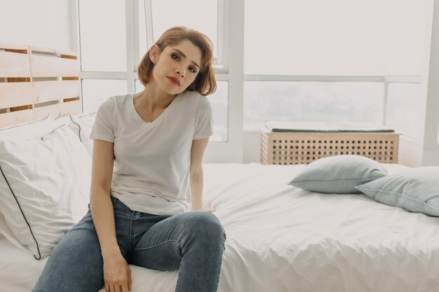 Cool look femme en t-shirt blanc et jean se détendre dans sa chambre d'appartement