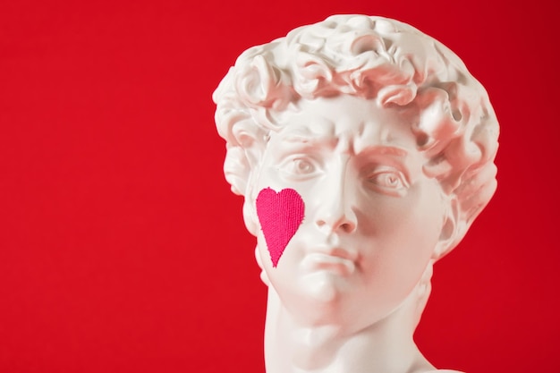 Une copie de la tête d'une statue antique de David avec un cœur rose collé sur la joue