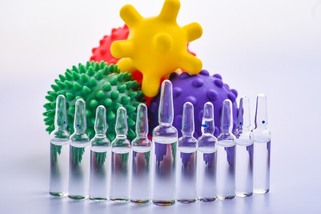 Copiez l'espace ampoules médicales transparentes dans une rangée. Jouets colorés pour enfants sous forme de virus. Les ampoules médicales protègent contre le virus. Isolé