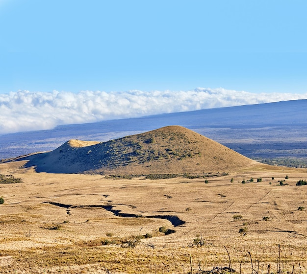 Copiez l'espace avec un cratère de volcan sur un horizon bleu nuageux Scène de nature stérile vide de champs d'herbe sèche sur une montagne et un sentier de randonnée Arrière-plan grand angle du Mauna Loa à Hawaï