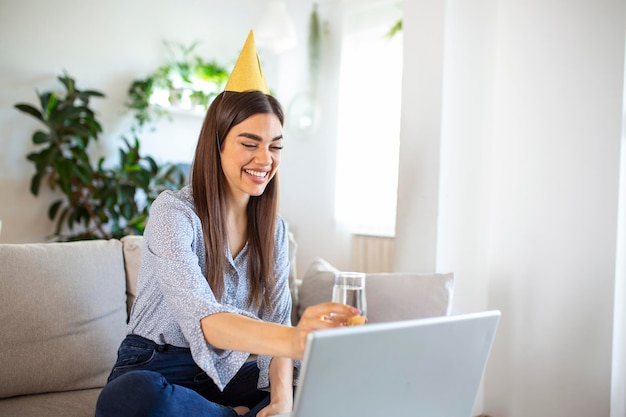 Copiez l'espace d'une jeune femme joyeuse organisant un événement de célébration d'anniversaire avec un ami lors d'un appel vidéo Elle porte un toast de fête avec un verre de vin blanc vers la caméra d'un ordinateur portable