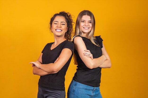 Copines blondes et afro sur fond jaune. Une femme blonde blanche et une brune afro, concept de diversité