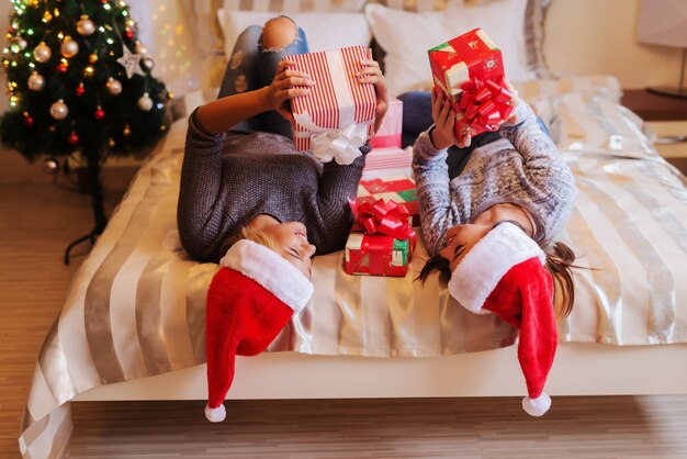 Copines couchées sur le lit et tenant des cadeaux.