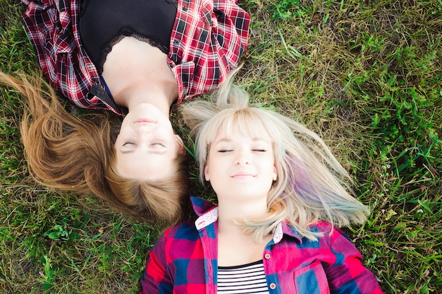 Copines couchées tête à tête sur l'herbe