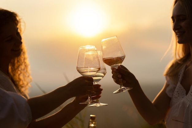 Photo copines portent un toast avec des verres de vin blanc sur un coucher de soleil