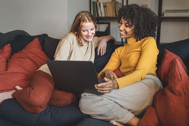 Copines utilisant un netbook assis sur le canapé dans le salon