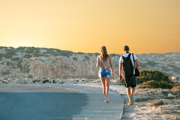 Les copines de voyage se promènent le long d&#39;une autoroute, sur fond de coucher de soleil et de la côte de la mer. Voyage et liberté, aventures et directions pour voyager