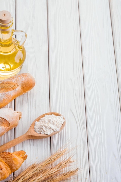 Copyspace image baguettes croissant épis de blé cuillère en bois avec de la farine bouteille d'huile sur de vieux tableaux blancs