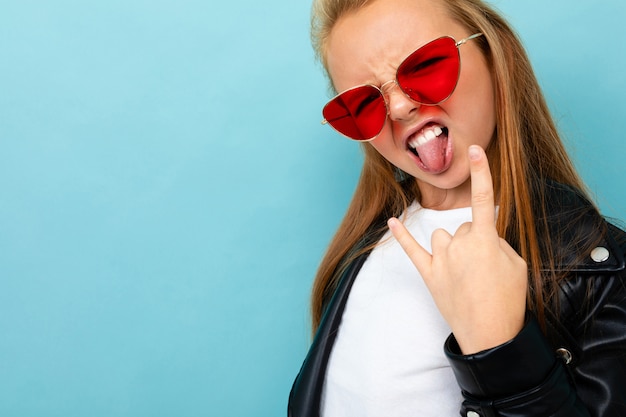 Copyspace photo d'adolescente charismatique content heureux sur un fond bleu de lunettes de soleil rouges