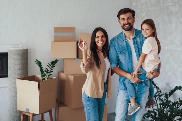 Copyspace photo d'un jeune couple excité et de leur jolie fille posant joyeusement dans leur nouvel appartement