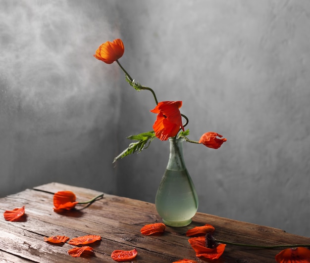 Coquelicots rouges dans un vase sur table en bois