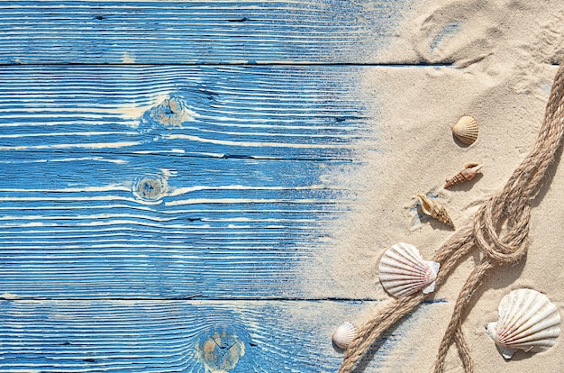 Photo coquillages et une corde avec du sable sur un fond en bois bleu