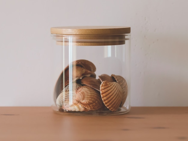 Coquillages dans un bocal en verre sur une table en bois