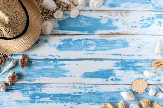 Coquillages sur planche de bois bleu avec chapeau de paille