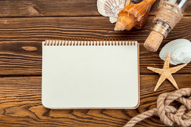 Coquilles et bloc-notes sur table en bois. Vue de dessus avec espace copie