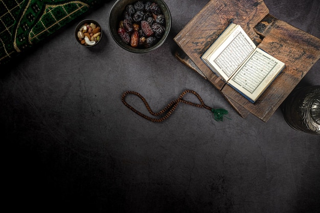 Photo coran ouvert près du concept de dates du ramadan kareem sur fond texturé sombre