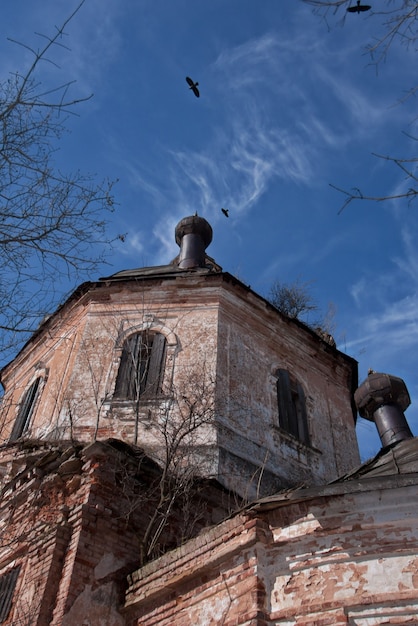 Corbeaux et nuages dans le ciel au-dessus de la vieille église ruinée dans le pays russe