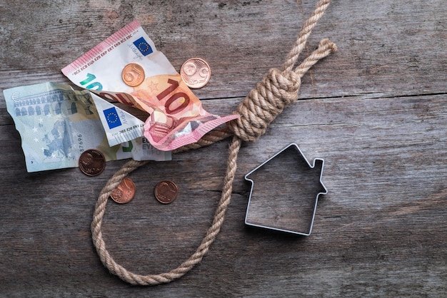 Corde du pendu avec clés de maison et argent sur une surface en bois marron