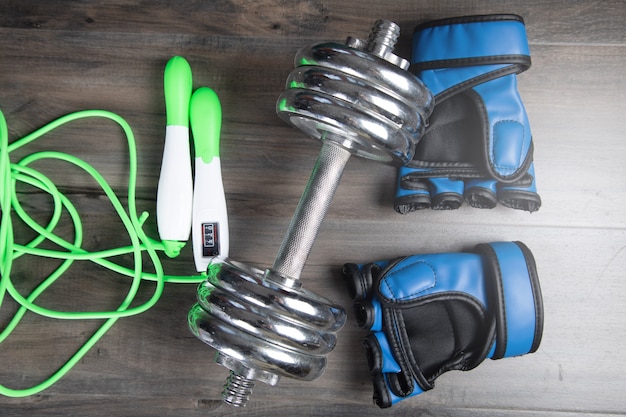 Corde à sauter, gants et haltères sur une table en bois