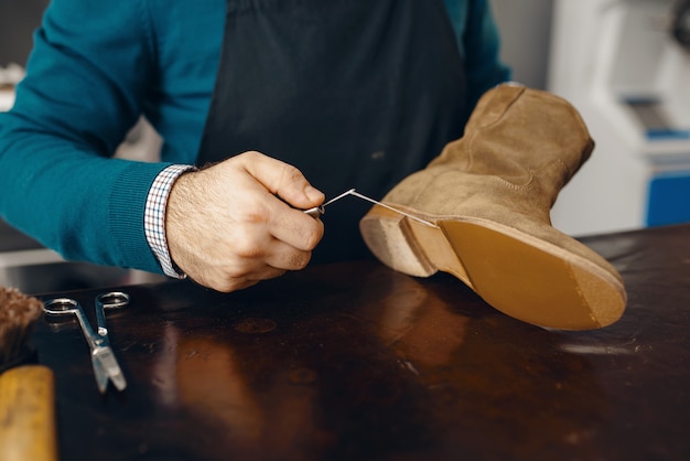 Le cordonnier coud la chaussure, service de réparation de chaussures