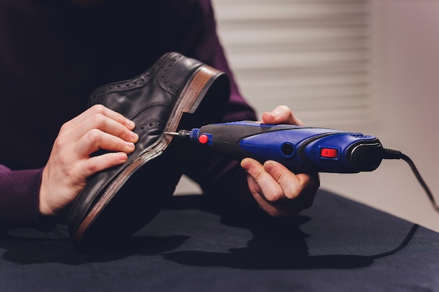 Un cordonnier coupe la semelle d'une chaussure avec un couteau automatique de cordonnier