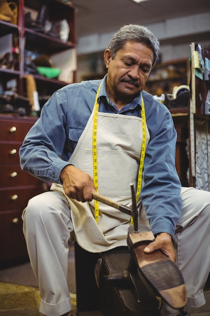 Photo cordonnier martelant sur une chaussure