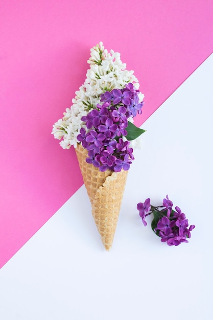 Cornet de crème glacée avec du lilas blanc et violet sur le fond coloré Espace de copie Emplacement vertical