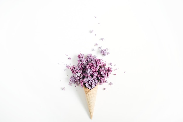 Photo cornet gaufré avec bouquet de fleurs lilas sur blanc