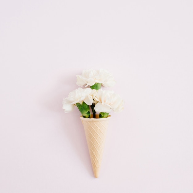 Photo cornet gaufré avec bouquet d'oeillets blanc sur rose pastel pâle