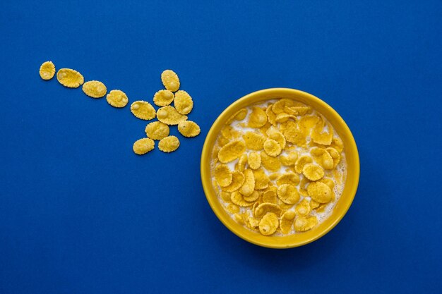 Cornflakes au lait dans le bol jaune sur fond bleu. Vue de dessus. Copie, espace vide pour le texte