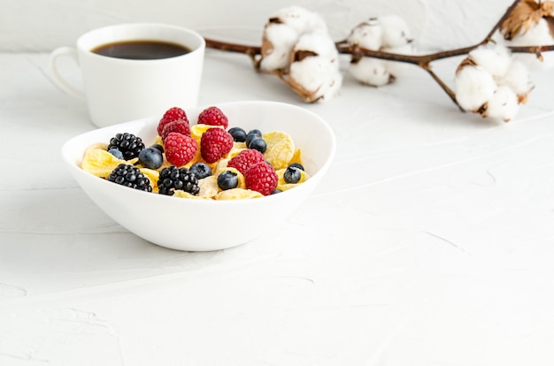 Cornflakes aux fruits frais sur une assiette sur une surface blanche