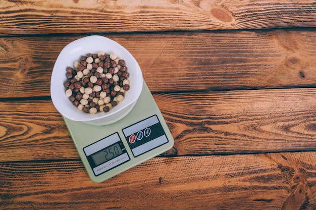 Cornflakes dans une assiette sur la balance sur un bois.