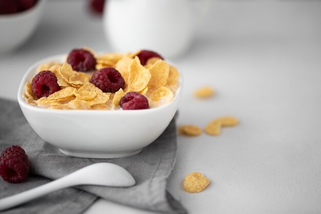 Cornflakes avec du lait et des framboises sur un tableau blanc