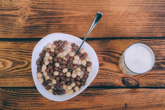 Cornflakes avec un verre de lait sur un bois.