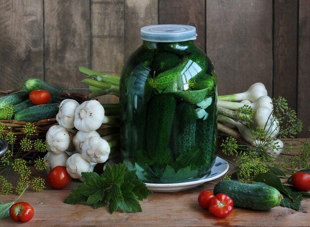 Des cornichons dans un bocal sur la table.