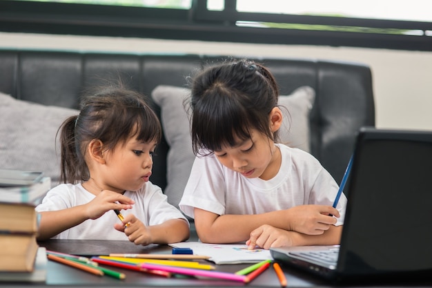 Coronavirus Covid-19 et apprentissage à domicile, concept d'enfant d'école à domicile. Les petits enfants étudient en ligne en apprenant à la maison avec un ordinateur portable.