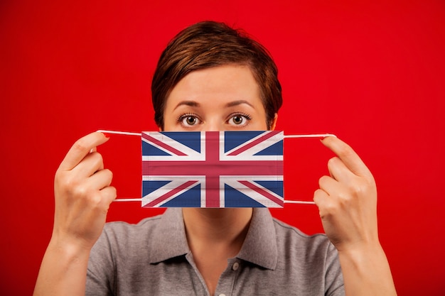 Coronavirus COVID-19 au Royaume-Uni. Femme au masque de protection médicale avec l'image du drapeau britannique.