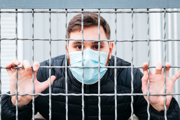 Coronavirus européen. Portrait d'un homme de race blanche portant un masque d'hygiène faciale, un masque de protection respiratoire en cage de quarantaine, arrêter le coronavirus. Virus, protection contre les coronavirus, pollution de l'air, écologie.