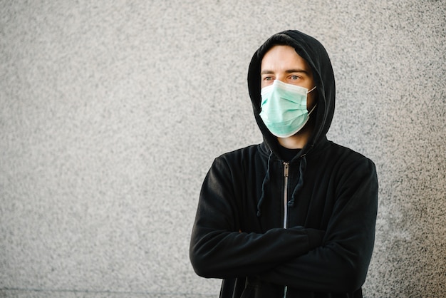 Coronavirus. Homme portant un masque de protection médical sur un mur gris. Prévenir Covid-19, grippe. Se sentir mal en ville. La personne a besoin d'aide. Virus, pandémie, concept de panique.
