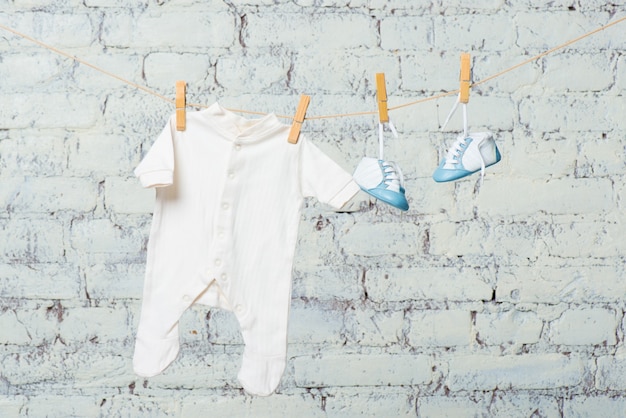 Corps blanc pour enfants et chaussures bleues sur une corde contre un mur de briques blanches