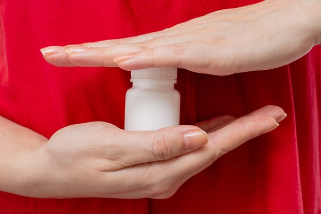 Un corps dans un t-shirt rouge tient une bouteille blanche