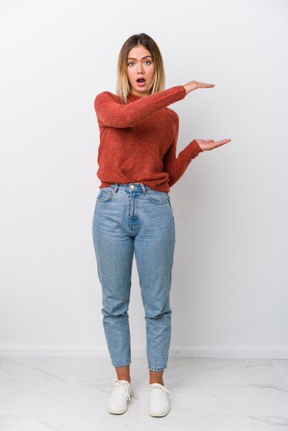 Corps entier jeune femme caucasienne choquée et étonnée tenant un espace de copie entre les mains.