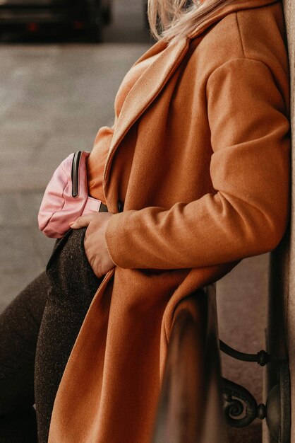 Corps féminin tête coupée dans le manteau chaud et confortable orange Portrait en plein air à la lumière du jour Vêtements d'hiver d'automne concept de style de rue