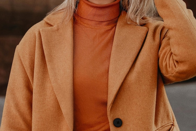 Corps féminin tête recadrée dans le chandail et le manteau chauds et confortables orange Portrait en plein air à la lumière du jour Vêtements d'hiver d'automne concept de style de rue