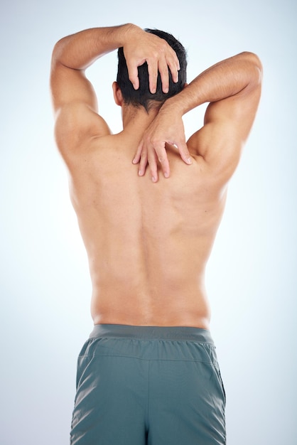 Corps de l'homme ou étirement des muscles du dos sur fond bleu en studio soulagement de la douleur soins de santé bien-être ou relâchement de la tension d'épuisement Modèle de fitness sportif ou entraîneur fléchissant lors de la vérification du succès de l'entraînement