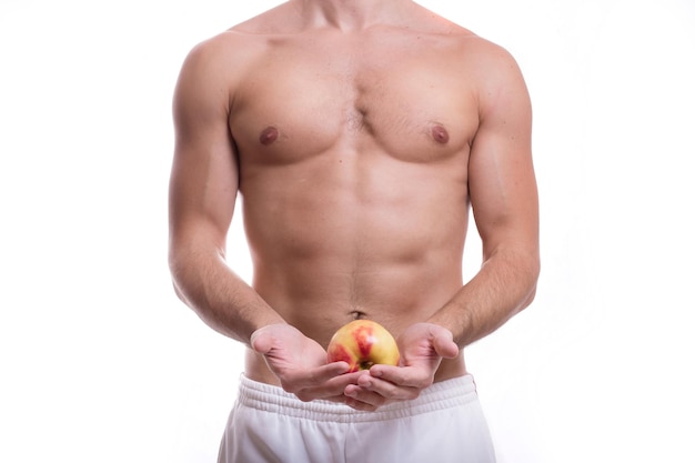 Corps d'un jeune homme de race blanche athlétique nu jusqu'à la taille isolé sur fond blanc avec une pomme à la main